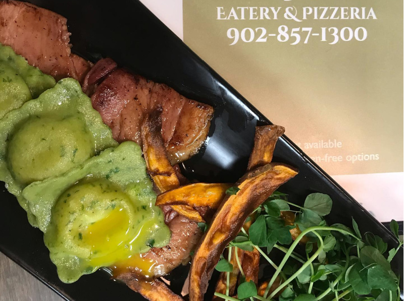 Three spinach ravioli encasing a silky egg yolk on top of maple glazed applewood smoked ham, served with crunchy sweet potatoes and micro greens
