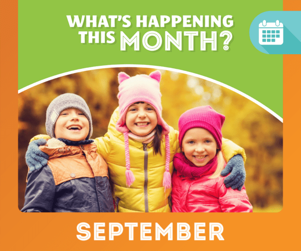 3 kids shoulder to shoulder smiling with fall clothing on with fall leaves in background