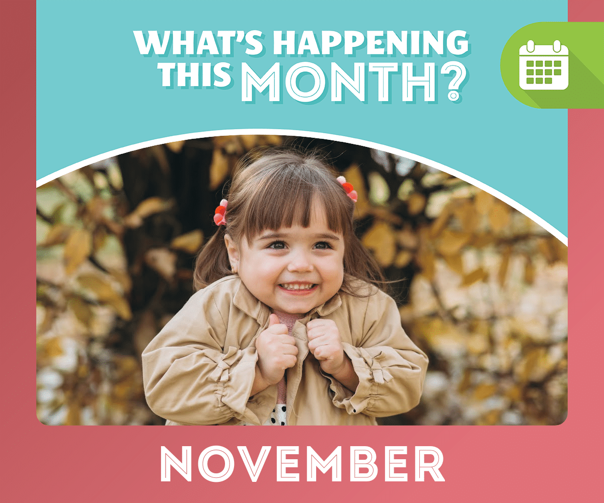 An excited little girl with fall leaves falling in the background