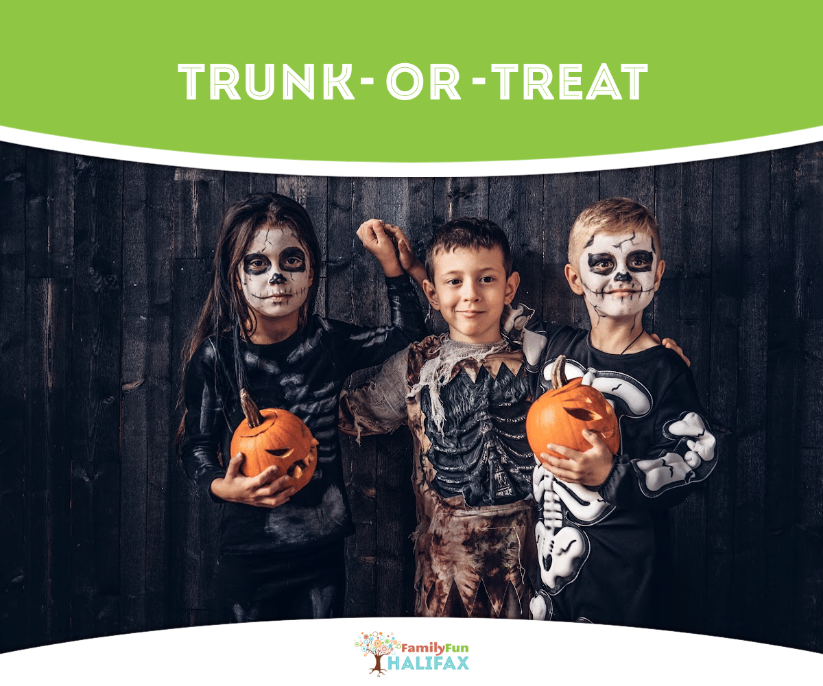 3 children in spooky costumes, the two on the ends are holding small pumpkins, dark wooden background