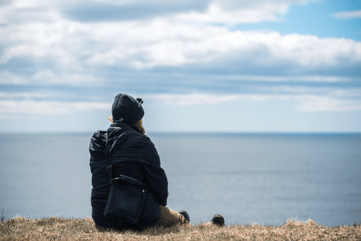 作為新斯科舍省東海岸定居游牧民族之旅的一部分，一名女子坐在懸崖頂上，俯瞰勞倫斯敦海灘