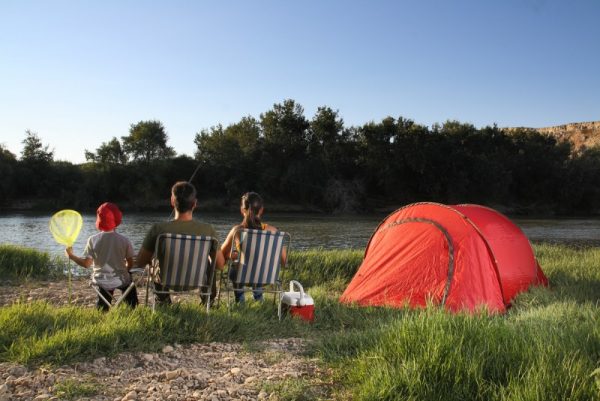 Família acampando em barraca à beira do rio