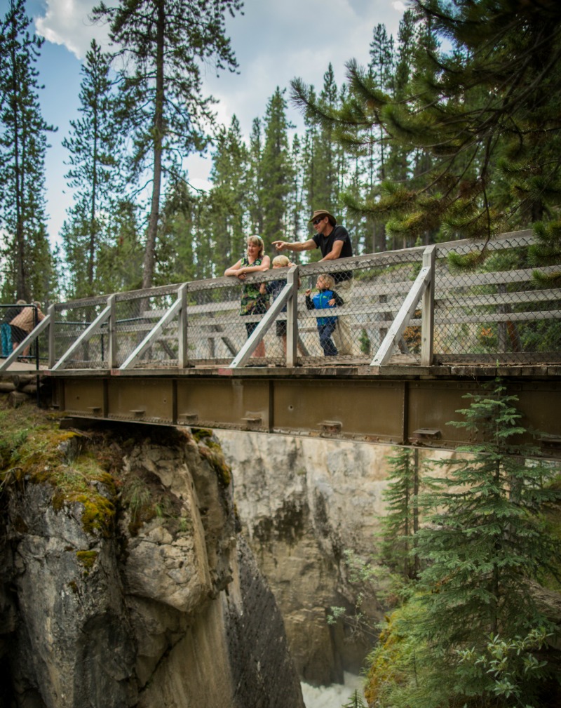 A young family looks at Sunwapta Falls from a viewpoint. Credit Parks Canada Ben Morin