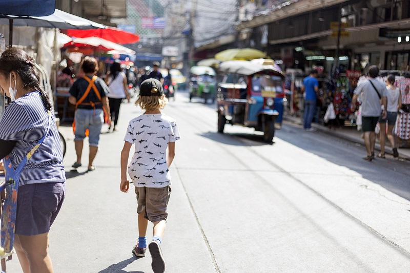 Kid friendly things to do in Bangkok - Boy walks among busy street vendors in Bangkok. Photo Credit Jennifer Morton