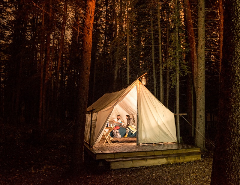 Посетители тусуются в своей освещенной палатке Métis Trapper во время ночлега. Национальный исторический памятник «Дом Роки Маунтин». Кредитные парки Канады - Скотт Манн