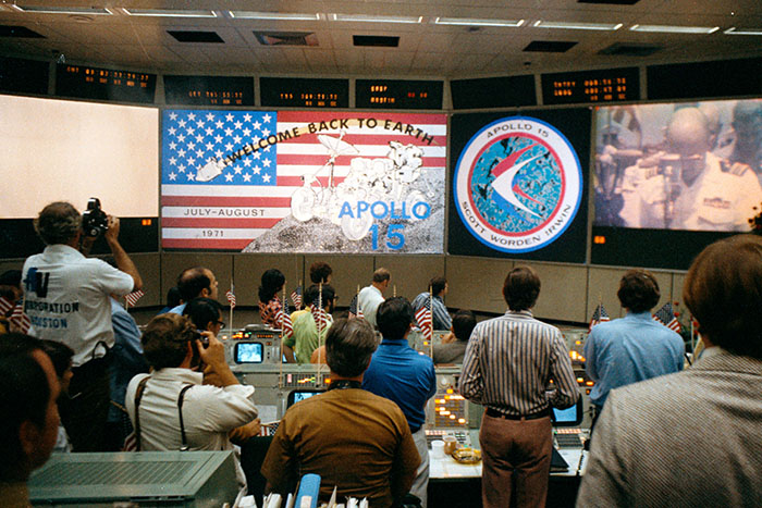 Photo credit: NASA Date Created: 1971-08-07 An overall view of activity in the Mission Operations Control Room in the Mission Control Center at the conclusion of the Apollo 15 lunar landing mission. The television monitor in the right background shows the welcome ceremonies aboard the prime recovery ship, U.S.S. Okinawa, in the mid-Pacific Ocean.