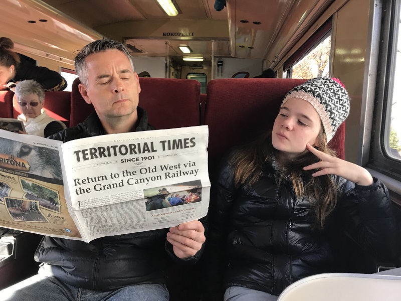 Blake Ford und Tochter Avery posieren beim Lesen der Territorial Times an Bord der Grand Canyon Railway_Foto von Lisa Kadane